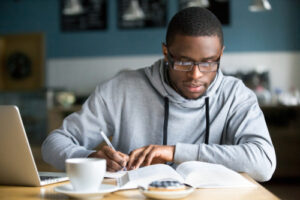 Focused,Millennial,African,American,Student,In,Glasses,Making,Notes,Writing